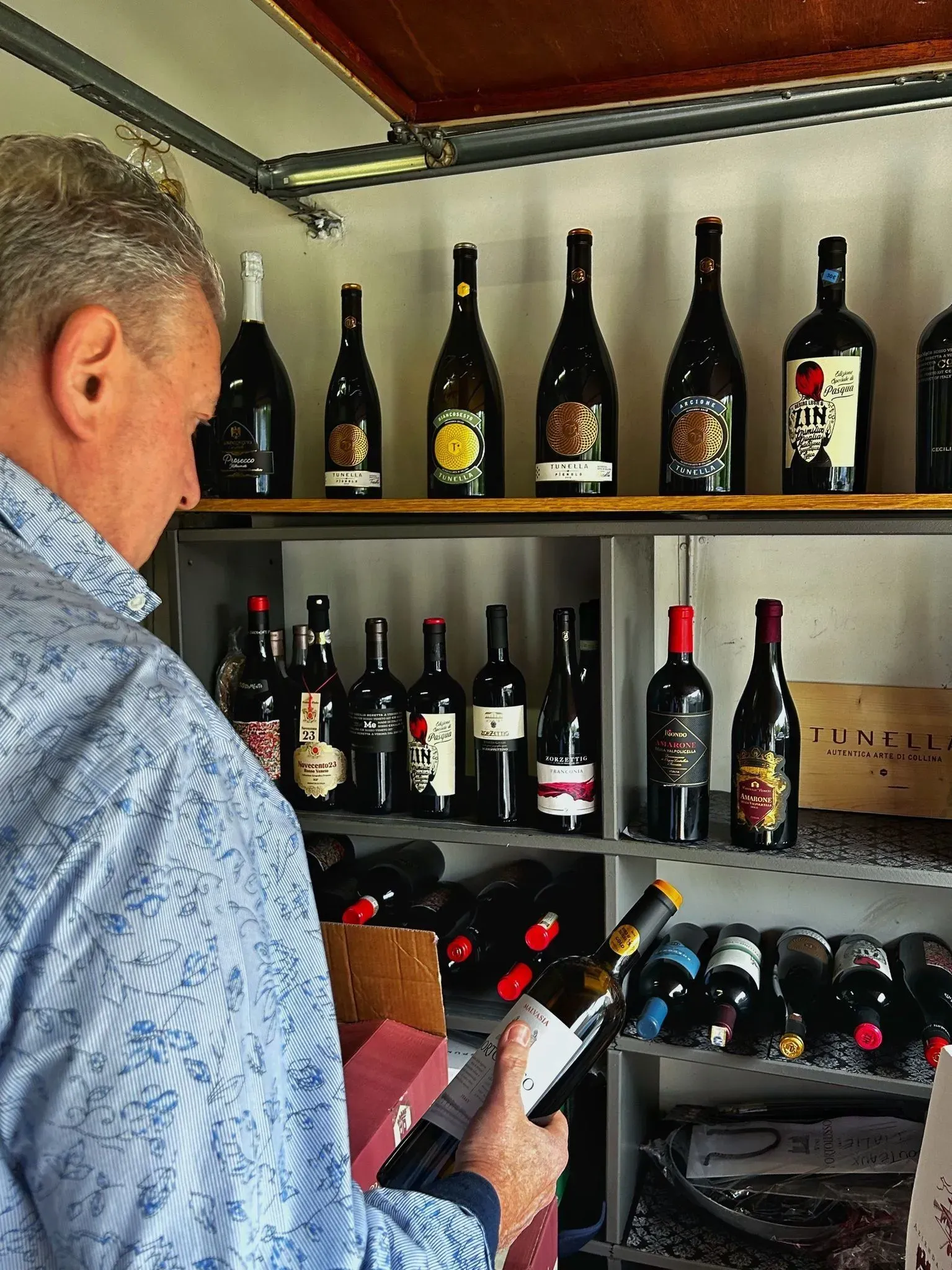 Daniel Drelli dans sa cave, choisissant une bouteille de vin italien
